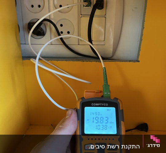 טכנאי רשת משתמש במכשיר מדידה לבדיקת כבלים